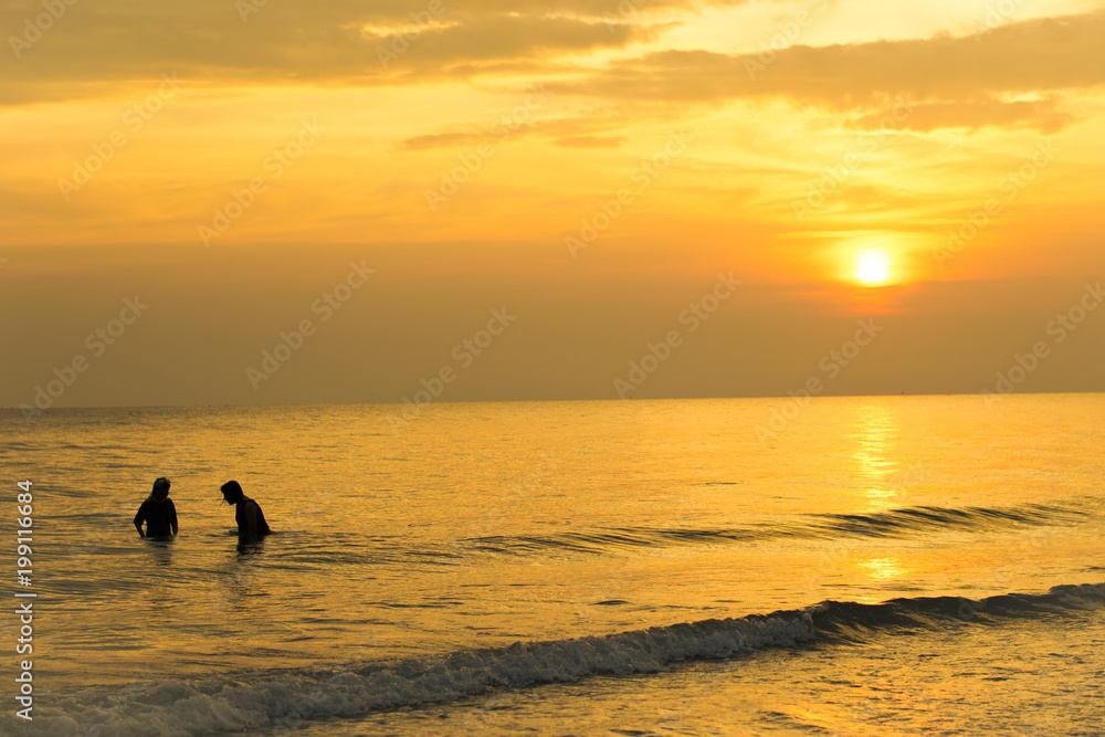 silhouette of a two woman playing water in sunset on the beach