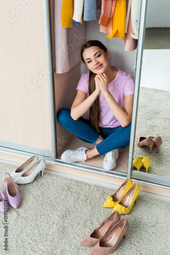 Quadro su tela attractive young woman sitting inside of cabinet with various shoes on floor at