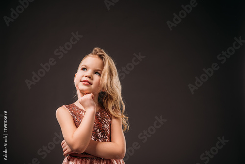 adorable thoughtful child in pink dress, isolated on grey