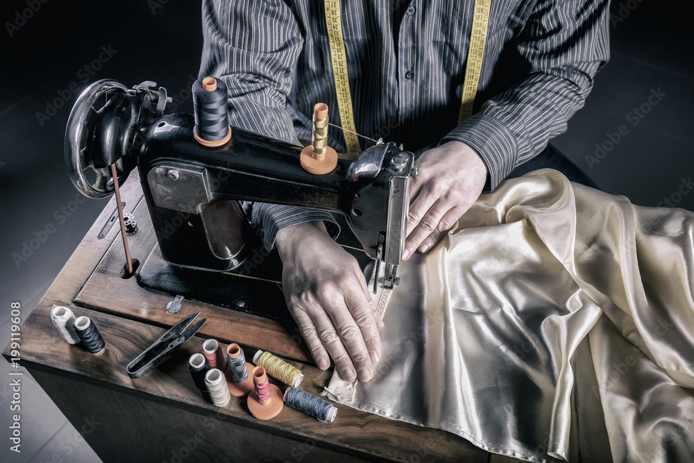 portrait and details of a tailor at work with an old and traditional sewing machine. manual and ancient work. portrait and details of a tailor at work with an old and traditional sewing machine. manual and ancient work.