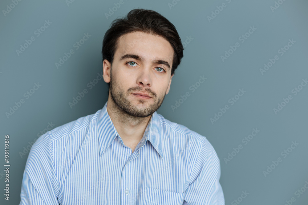Handsome man. Pleasant nice bearded man standing against grey background and looking at you while being serious Handsome man. Pleasant nice bearded man standing against grey background and looking at you while being serious
