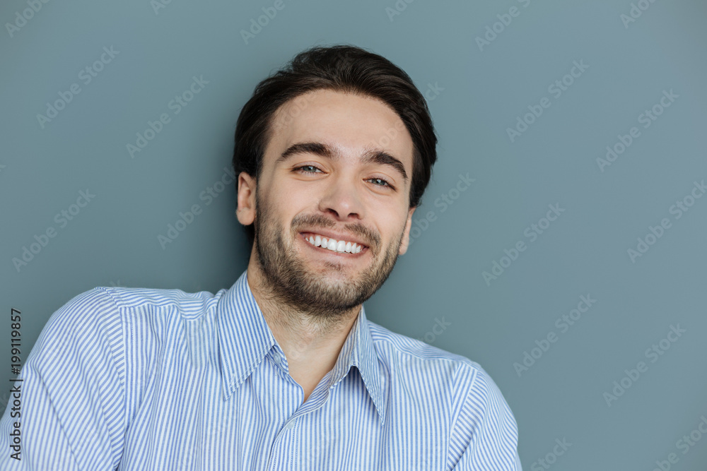 Cheerful smile. Portrait of a nice handsome young man smiling while being in a wonderful mood Cheerful smile. Portrait of a nice handsome young man smiling while being in a wonderful mood