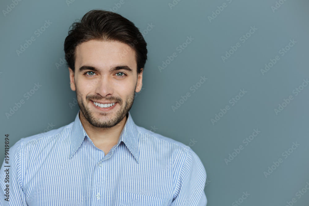 Facial expression. Portrait of a nice cheerful brunette man looking at you while showing his positive smile Facial expression. Portrait of a nice cheerful brunette man looking at you while showing his positive smile