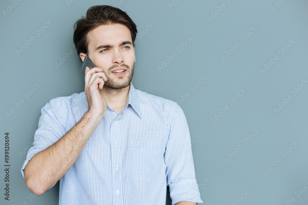 Phone communication. Smart nice confident man standing and putting a phone to his ear while making a call Phone communication. Smart nice confident man standing and putting a phone to his ear while making a call