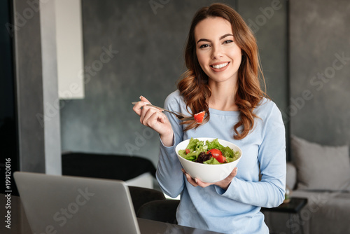 Portrait of a happy young woman eating fresh salad