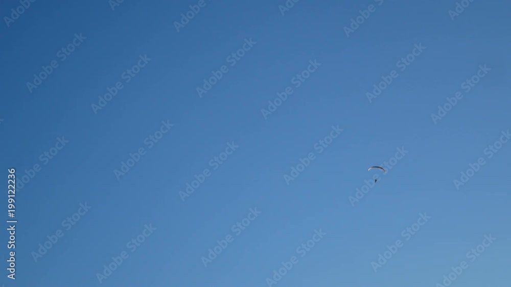 4K parachute activity. colorful parachute wing flying with passenger in the blue cloudy sky, extreme sport, summer activities at the beach 4K parachute activity. colorful parachute wing flying with passenger in the blue cloudy sky, extreme sport, summer activities at the beach