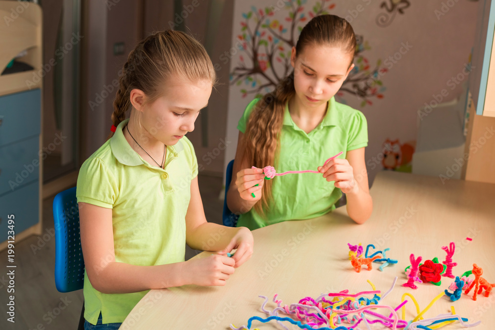 Fototapeta premium Cute little girls creating toys with chenille sticks