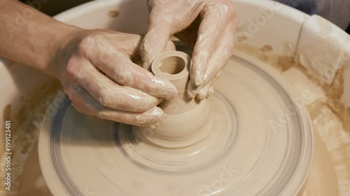 Male craftsperson sculpt process on the round potterswheel closeup isolated. Artisan dexterity creating product - cup or vase from wet brown mud. Lifestyle, leisure, creativity concept of background photo