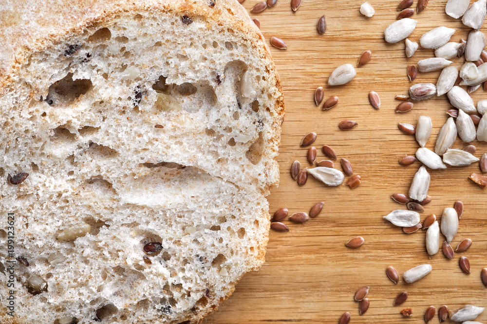 Loaves of gray bread with seeds, in a paper bag, lie on a black table made of wood. Loaves of gray bread with seeds, in a paper bag, lie on a black table made of wood.