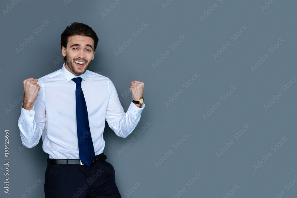 This is great. Joyful nice delighted man looking at you and smiling while celebrating his success This is great. Joyful nice delighted man looking at you and smiling while celebrating his success