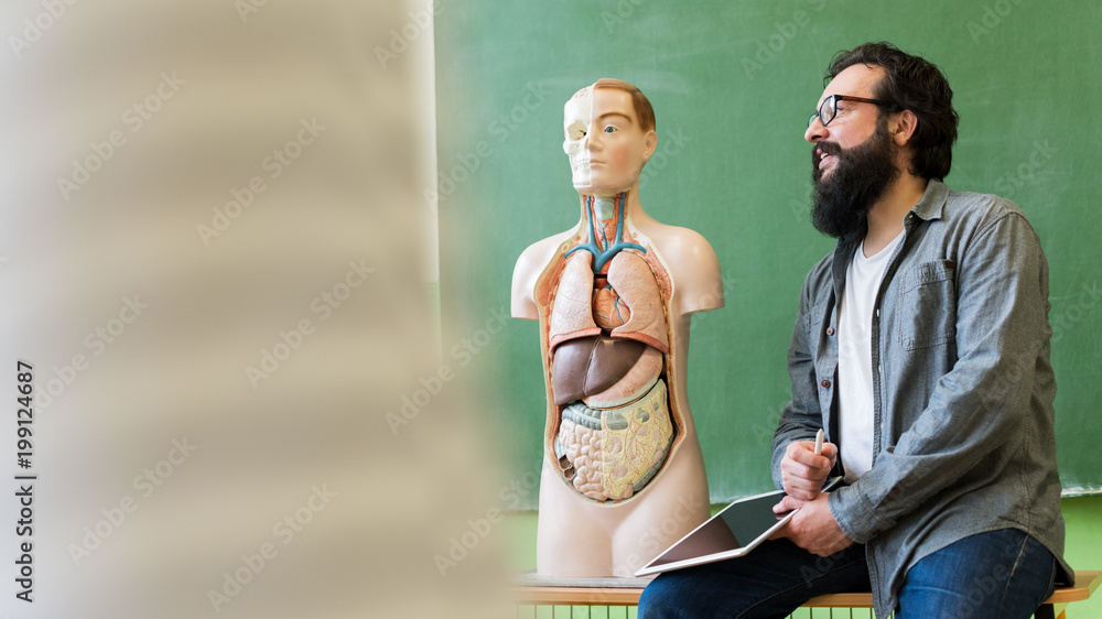 Young male hispanic teacher in biology class, holding digital tablet ...