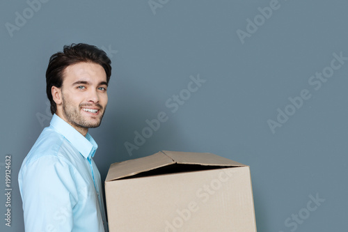For things. Cheerful happy nice man smiling and holding the box while looking inside it