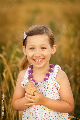 Happy girl in wheat field on warm and sunny summer evening