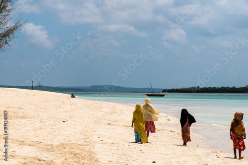 Тraditional African Muslim girls on walking along the beach of the ocean.Zanzibar