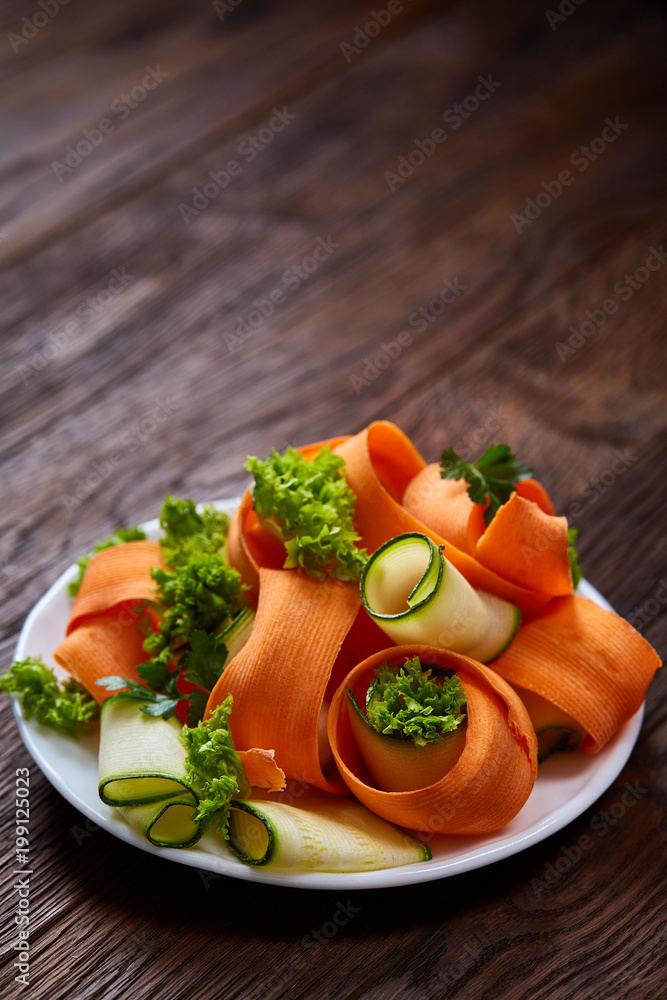 Artistically served vegetable salad with carrot, cucumber, letucce over wooden background, selective focus Artistically served vegetable salad with carrot, cucumber, letucce over wooden background, selective focus