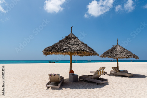 Beach Chairs and Umbrella on a beautiful island, panoramic view with much copy space,swimsuits, beautiful cloudy sky