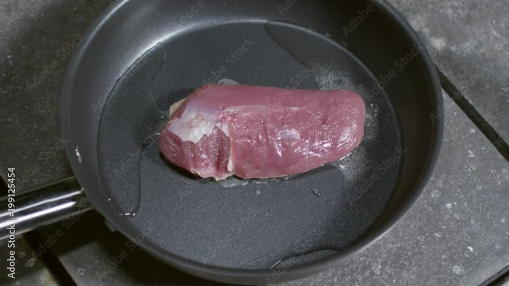Piece of unrecognizable cook salting piece of raw duck meat frying in pan with olive oil Piece of unrecognizable cook salting piece of raw duck meat frying in pan with olive oil