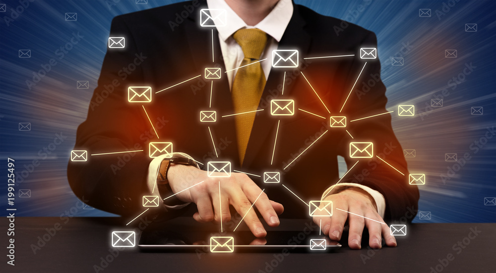 Businessman in suit typing with connected mail icons around 