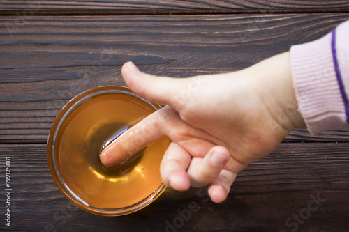 baby hand holding a finger in the honey on wooden table