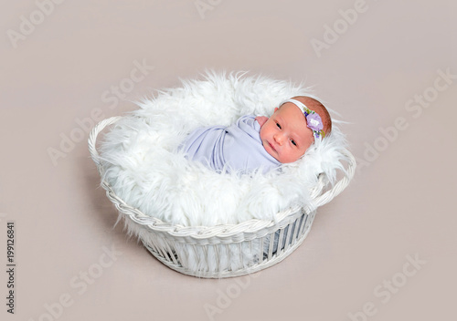 Lovely newborn baby girl wrapped in a purple cocoon