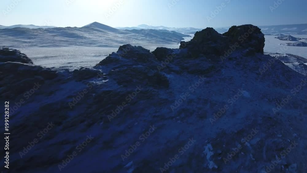 Cinematic blue dark rock cliff texture top of mountain. Deep blue shadows. Unique Lake Baikal russia landscape. Winter snow field frost season. Journey abandoned descent. Aerial Helicopter Approach Cinematic blue dark rock cliff texture top of mountain. Deep blue shadows. Unique Lake Baikal russia landscape. Winter snow field frost season. Journey abandoned descent. Aerial Helicopter Approach