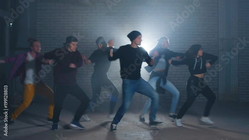 Group of street dancers performing different moves on the dark street.