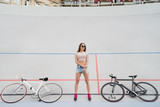 Cycling and fitness. Young beautiful fit woman with perfect body in sportswear near the bikes outdoors on the track. Sportive and healthy lifestyle, cyclist working out, training, fashion, beauty.