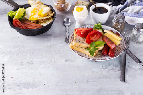 English breakfast. Fried eggs, sausages, toasts, tomatoes on stone table.