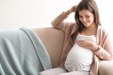 Young pregnant woman sitting on couch in living room