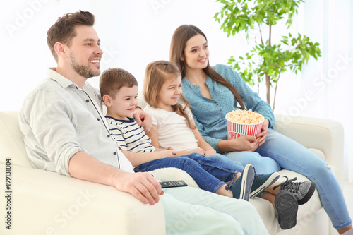 Family watching TV on sofa ...