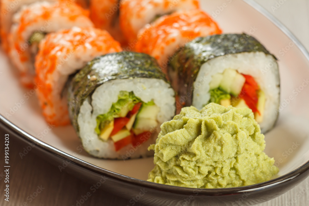 Close up wasabi and sushi rolls with vegetables, Uramaki California on the background. Japanese cuisine