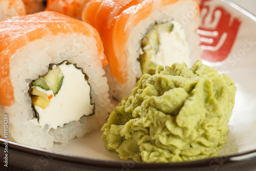 Close up Uramaki Philadelphia. Sushi rolls with salmon, nori, rice, Philadelphia cheese, pieces of avocado, cucumber and wasabi