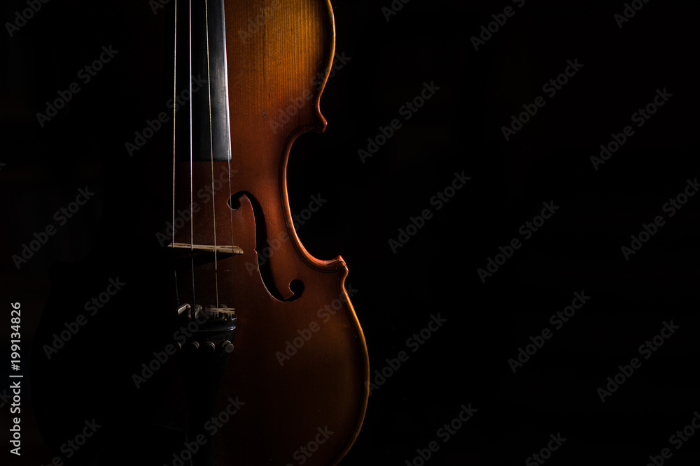 Violin on a black background lit from one side Violin on a black background lit from one side
