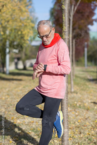 Fototapeta Naklejka Na Ścianę i Meble -  Senior runner man resting at the park while monitoring his exercise