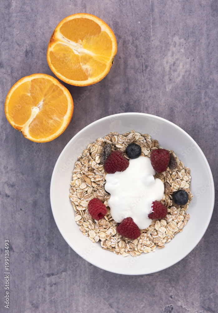 Vertical image of a bowl of Muesli with two orange halves on a blue stone background Vertical image of a bowl of Muesli with two orange halves on a blue stone background