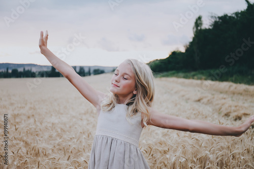 Smiling girl stretching in a wheat field.