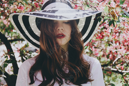 Girl in a hat in blossoming trees.