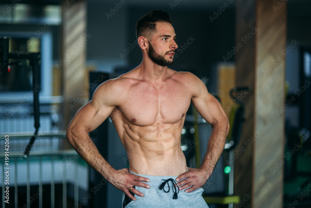 Fototapeta premium A young athlete trains in the gym. Shows the muscles