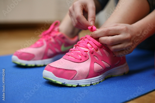 Woman tying the shoelaces of her fitness shoes.