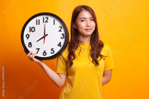 Young Asian woman with a clock in yellow dress