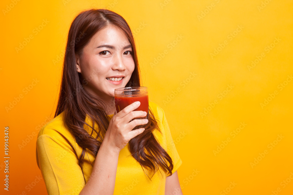 Young Asian woman drink tomato juice in yellow dress Young Asian woman drink tomato juice in yellow dress