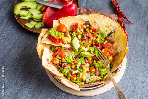 Spicy Mexican vegetarian taco salad with avocado, corn, pepper, tomatoes and beans
