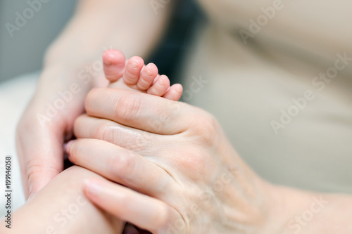 Mother making feet massage for infant baby. Parent care about kid. Children health car and disease prevention