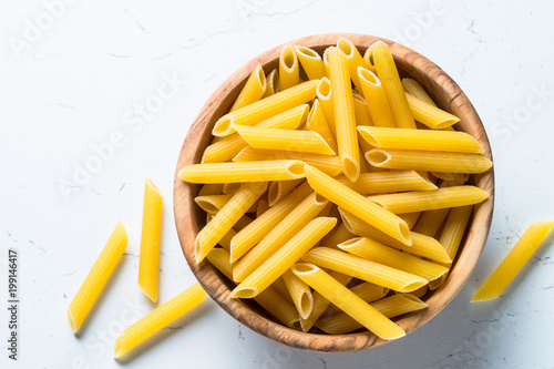 Pasta penne  in wooden bowl on white table. 