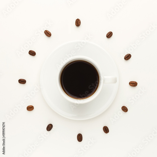 Black coffee cup and roasted beans forming clock dial isolated on white