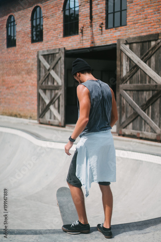 rear view of handsome skater putting leg on longboard
