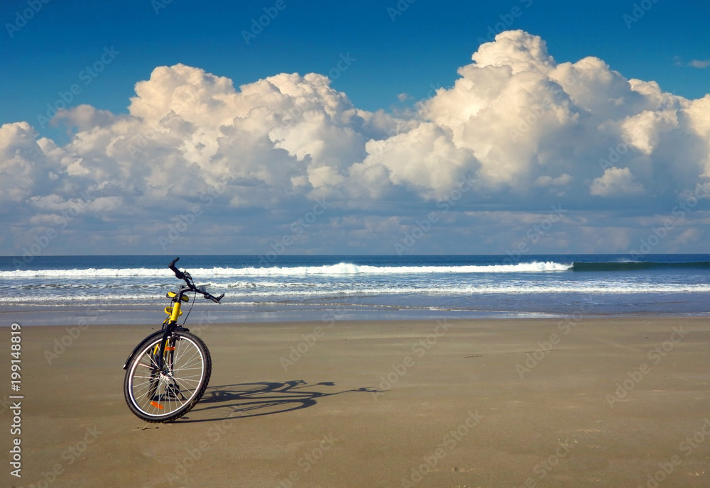 Obraz premium yellow bicycle on the beach by the sea in sunny weather