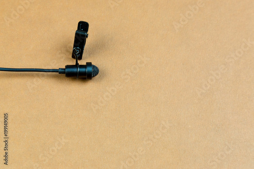 Miniature microphone of the buttonhole. A small microphone for recording quality sound on a brown background. photo