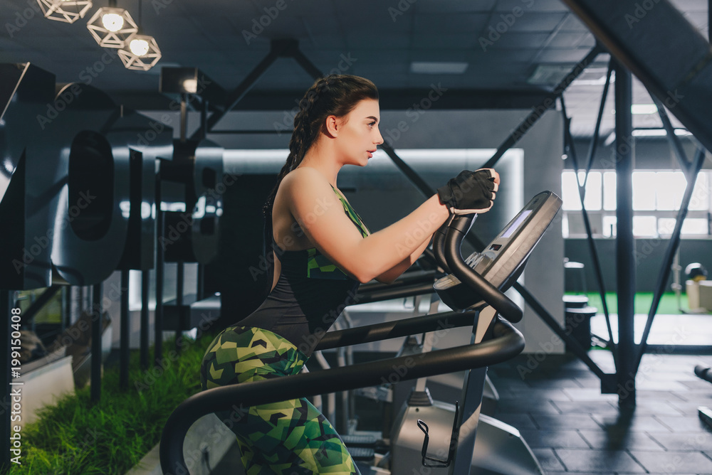 Fototapeta premium Girl working on the stepper in the gym. Healthy lifestyle. Fitness concept.
