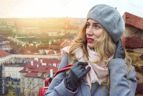 Woman in Prague. Czeh Republic. Beautiful blonde lady smiling with red lips dressed in gray. City scape background view photo